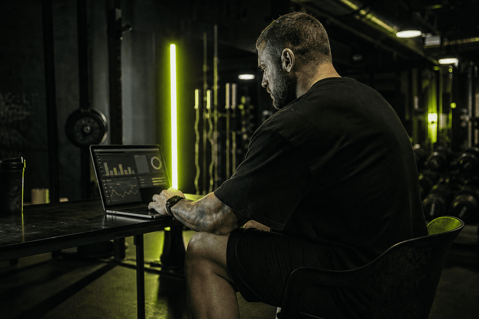 Fitness coach reviewing agent drafts on a laptop in the gym